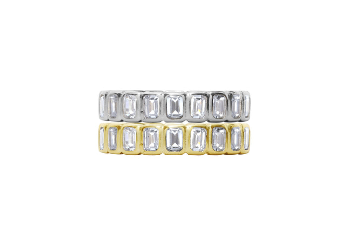 Two gold and silver rings with emerald-cut gemstones on a white background